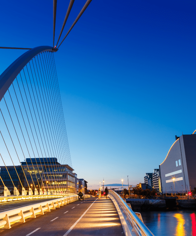 The sky reflects off the water, illuminating the Samual Beckett bridge, buildings, roads, and architecture of Dublin city.