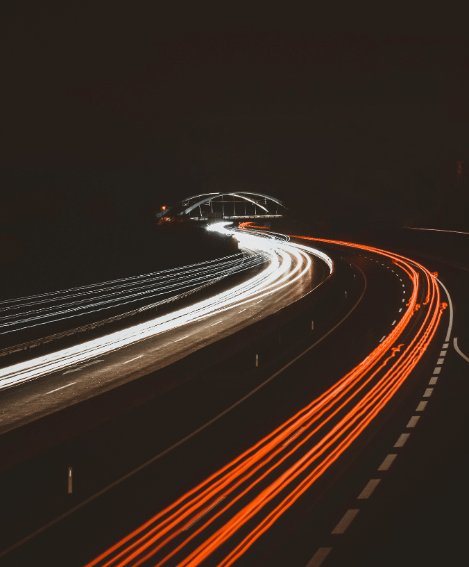Cars speed along the illuminated freeway, navigating the transport corridor of roads, streets, and highways at night.