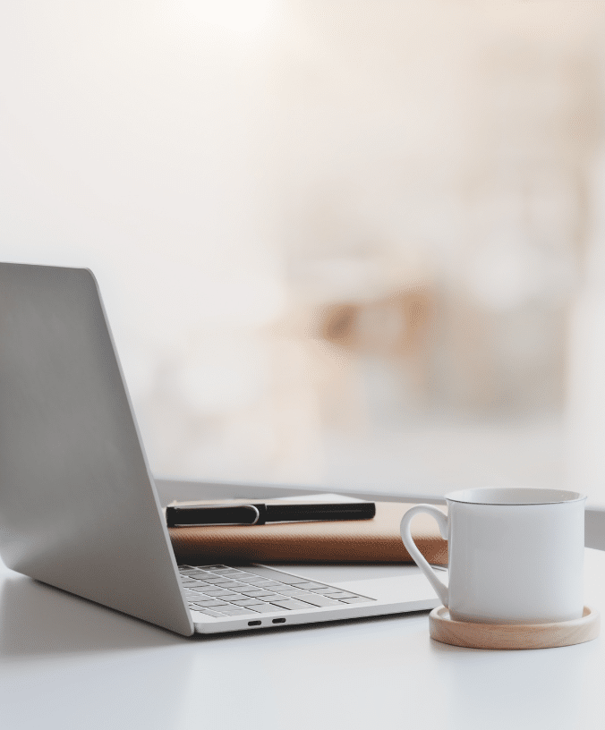 A person is using a laptop and drinking a cup of coffee.