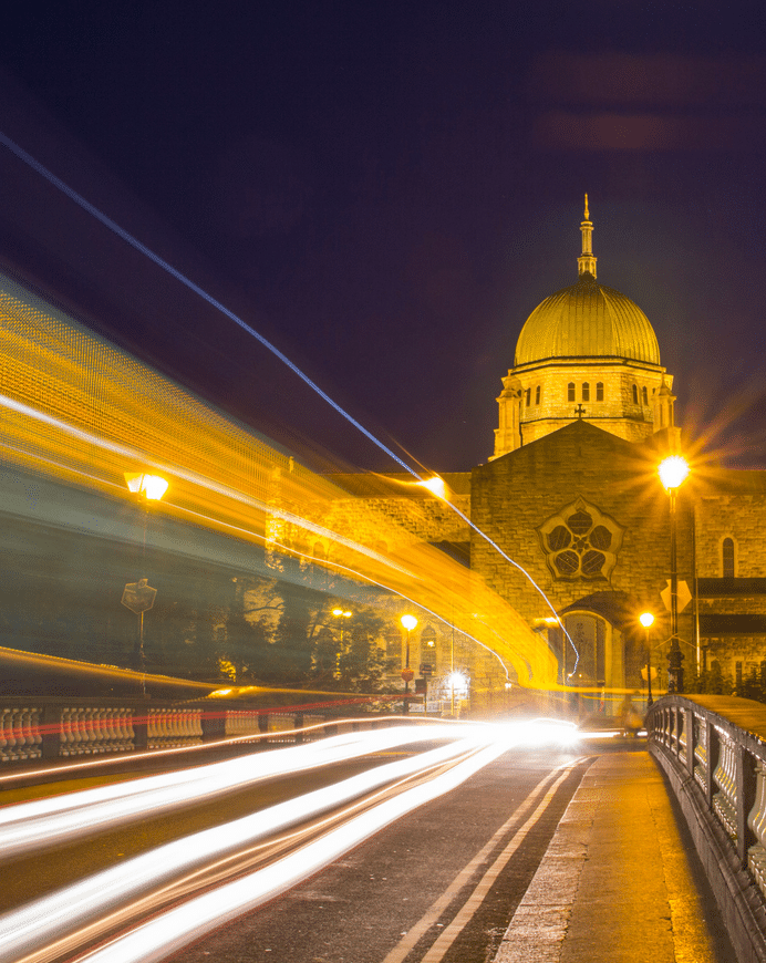 Long exposure photo capturing light trails from night traffic on a Galway city street with a domed building in the background, showcasing the dynamic nature of web hosting technology.